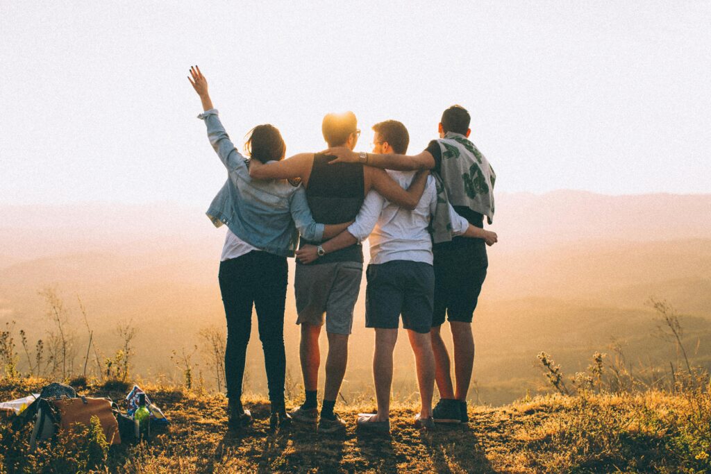 pexels-photo-4453153-4453153 A group of friends embrace while enjoying a sunset view from the mountain top.